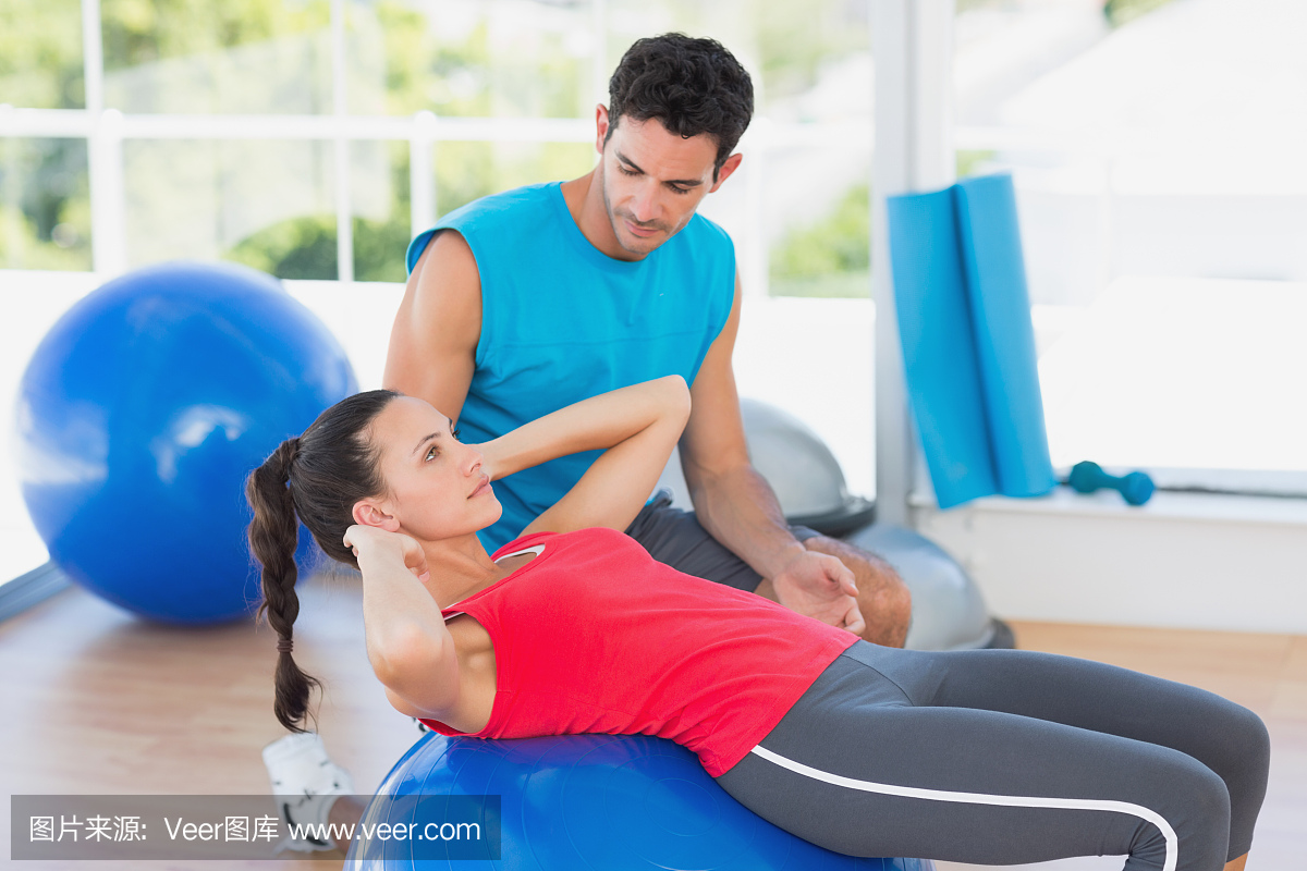 男教练在健身房帮助女性锻炼